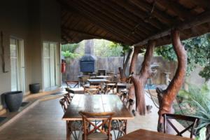 - un ensemble de tables et de chaises sur une terrasse dans l'établissement Croc River Lodge, à Komatipoort