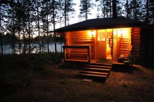 a small log cabin with lights on in the woods at Mökki Jyväskylä in Nyrölä