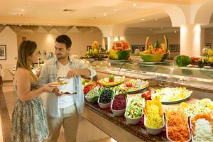 Ein Mann und eine Frau stehen vor einem Buffet. in der Unterkunft HSM Reina del Mar in El Arenal