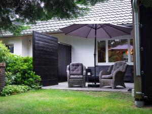 2 sedie e un ombrellone su un patio di Lagom bed and breakfast a Wilsum