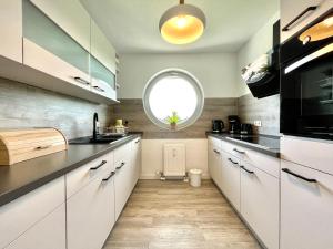 a kitchen with white cabinets and a round window at Apartment Rooftop in Dresden