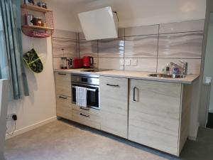 una cocina con armarios de madera y fregadero en Relax in a 1 Bedroom Apartment near a country Pub, en Eyemouth