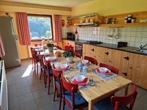 une cuisine avec une grande table en bois et des chaises rouges dans l'établissement Sneeuweifel, à Burg-Reuland