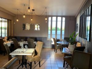 a restaurant with tables and chairs and a mirror at L'ESCALE FONTAINE SIMON in Fontaine-Simon