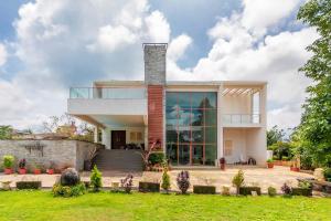 a house with a large window and a lawn at Arihant Villa by StayVista - 5BHK Luxurious Villa with Pvt Pool in Lonavala