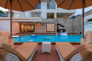 a swimming pool with two chairs and an umbrella at Arihant Villa by StayVista - 5BHK Luxurious Villa with Pvt Pool in Lonavala