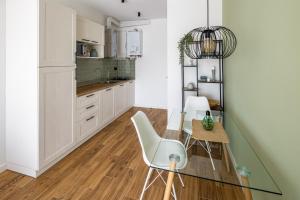 利沃夫New building on Shevchenko Street, center的厨房配有白色橱柜和玻璃桌及椅子