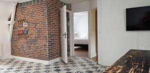 a room with a brick wall and a tv at Les 3 mômes in Pontorson