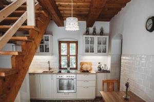 uma cozinha com armários brancos e um tecto de madeira em Andante Vendégház em Vászoly