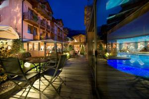 a hotel patio with a swimming pool at night at Sporthotel Rosatti in Dimaro