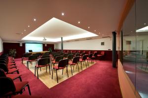a conference room with red chairs and a red carpet at Sporthotel Rosatti in Dimaro +84 photos