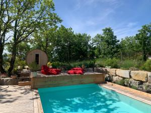 un patio trasero con piscina y pared de piedra en Maison d'Hôtes de Charme Le Clos de la Fontaine Piscine & SPA en Labastide-Marnhac