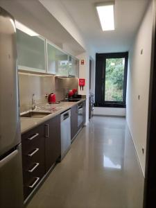 une grande cuisine avec des appareils électroménagers blancs et une grande fenêtre dans l'établissement Confort4you Apartment, à Gerês