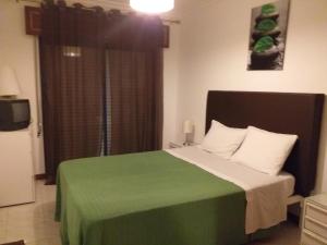 a bedroom with a green and white bed with a window at Quarteira T1 - Oceanides in Quarteira