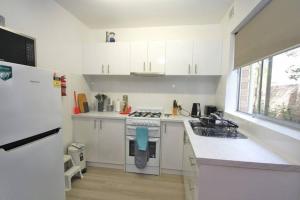 uma cozinha branca com um fogão e um frigorífico em LOCATION LIFESTYLE CONVENIENCE! WIFI NETFLIX WINE em Perth