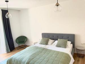 ein Schlafzimmer mit einem Bett mit einer grünen Decke und einem Stuhl in der Unterkunft Rosa's Boutique Apartment & parking in Meran