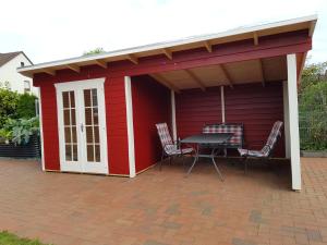 a red shed with a table and chairs on a patio at Ferienwohnungen Liliencron - Fewo I in Enger