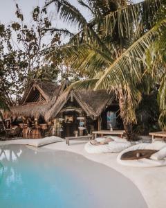 a resort with a swimming pool and a resort with palm trees at La Cabane in Jimbaran