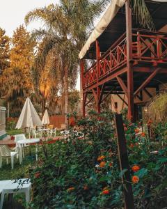 un jardín con mesas, sillas y flores en Hotel Los Pinares en San Pedro