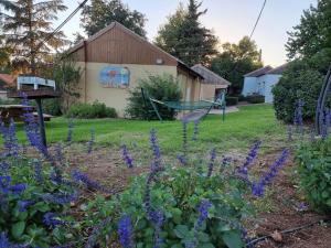 - un jardin avec des fleurs violettes et un hamac dans l'établissement הצימר של אורנה, à Odem