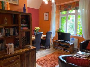 a living room with a television and a table with chairs at Penmachno Hall - self catering suite in Betws-y-coed