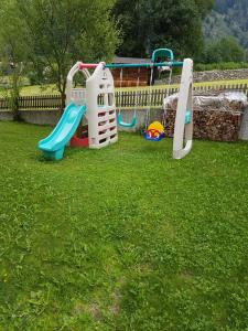 a playground with two swings and a slide in the grass at Apartments Nature Apis Landheim in Anterselva di Mezzo