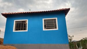Una casa azul con dos ventanas. en Casa Nascer do Sol, en São Thomé das Letras