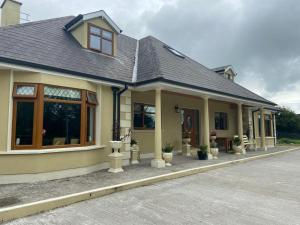 a house with a porch with potted plants at Motorwaylodge Kilcoran Cahir E21RK60 in Cahir