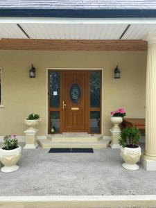 a front door of a house with two vases at Motorwaylodge Kilcoran Cahir E21RK60 in Cahir