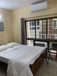 a bedroom with a bed and a large window at Pearl by Olys Apartment in Kolkata