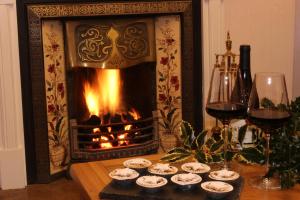 a fireplace with some cupcakes and wine glasses on a table at Woodlands Country House & Cottage in Ireby