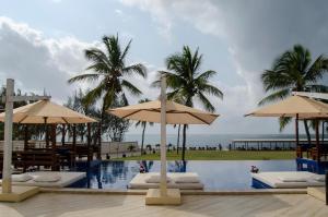 a pool with umbrellas and the ocean in the background at Jumeirah Beachfront in Mombasa