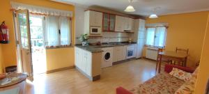 cocina con paredes amarillas, armarios blancos y mesa en Apartamentos Casa Alvarina - Luarca, en Cortina