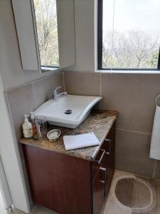 ein Bad mit einem Waschbecken und einem Spiegel in der Unterkunft CityView, a stunning modern apartment in Johannesburg