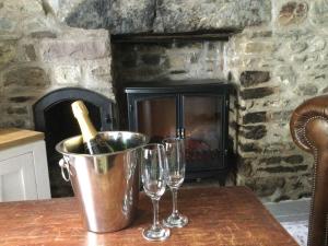two wine glasses and a bucket on a table with a fireplace at bwthyn y porthmyn in Llandovery