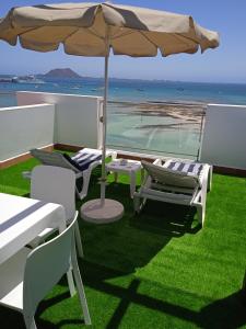 a patio with an umbrella and chairs on the grass at On the Beach in Corralejo