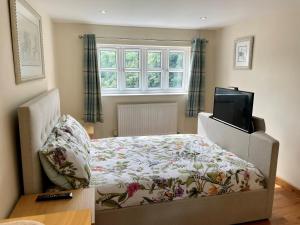 a bedroom with a bed and a flat screen tv at The Annex at Pantglas Farm in Pontyclun