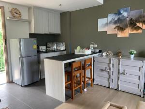 a kitchen with a refrigerator and a counter with stools at The Valley Khao Yai in Ban Huai Sok Noi