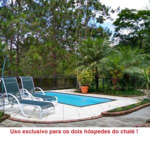 a patio with two chairs and a swimming pool at Chalé Meu Agresthe in Teresópolis