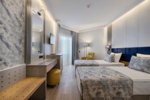 Sealife Kemer Resort Hotel - Ultra All Inclusive في كيمير: غرفة فندقية بسريرين واريكة
