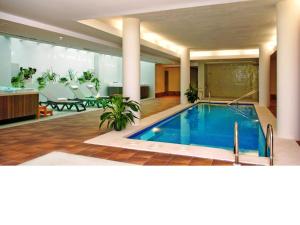 einen Pool in einer Lobby mit einem Tisch und Stühlen in der Unterkunft Ballesol Costablanca Senior Resort mayores de 55 años in Cala de Finestrat