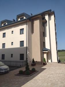 un gran edificio blanco con un coche aparcado delante de él en Apartman Viktor & Matej Zlatibor, en Zlatibor