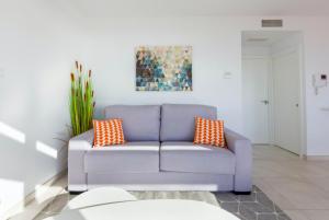 a blue couch with orange pillows in a living room at Seafront Boutique CalaBeach in Cala del Moral