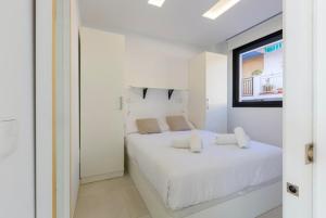 a white bedroom with a white bed and a window at Seafront Boutique CalaBeach Rincón de la Victoria in Cala del Moral