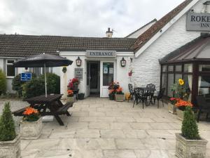 een patio met tafels en een parasol voor een gebouw bij Rokeby Inn in Newsham