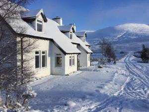 una casa blanca en la nieve con una montaña en Balsporran Bed and Breakfast, en Dalwhinnie
