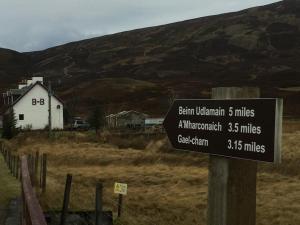 a sign in front of a building in a field at Balsporran Bed and Breakfast in Dalwhinnie