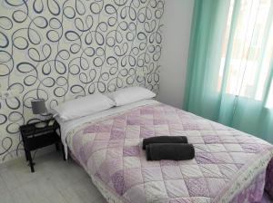 a bedroom with a bed with a purple and white comforter at Apartamentos CENTRO HISTORICO in Málaga