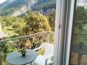 a balcony with a table and chairs and a view of a mountain at Le Relais des Cavaliers in Villeneuve-dʼEntraunes