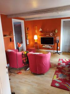 uma sala de estar com duas cadeiras cor-de-rosa e uma televisão em Lilla Röda Halmstadby 3524, Kågeröd em Kågeröd
